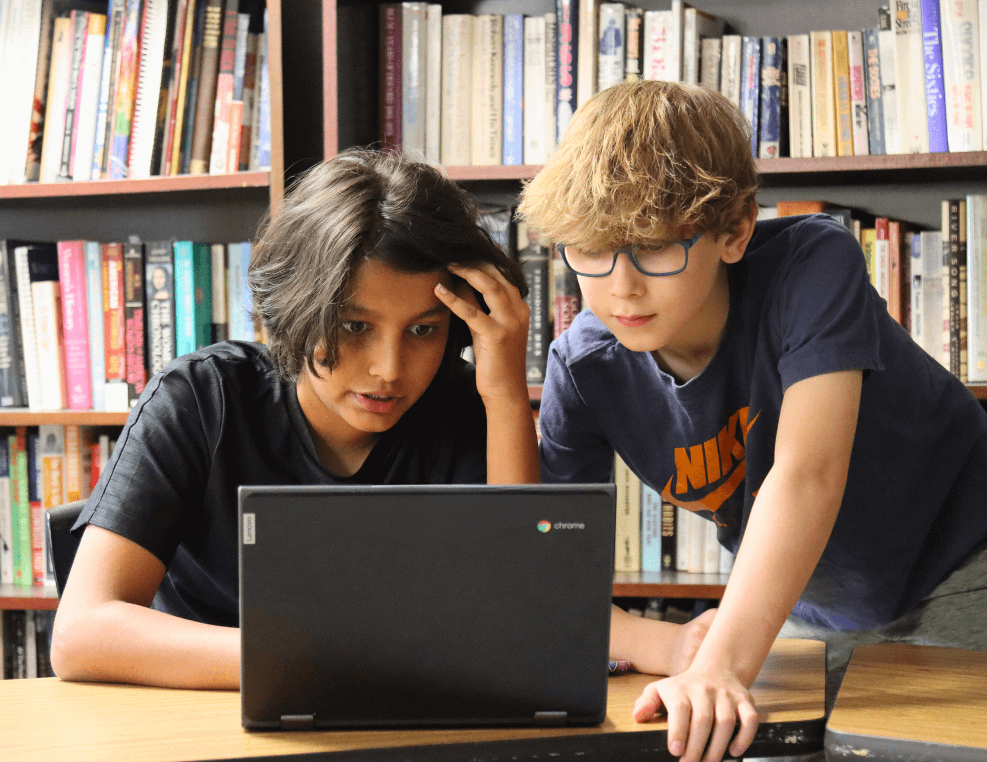 two middle school boys working together on a chromebook.