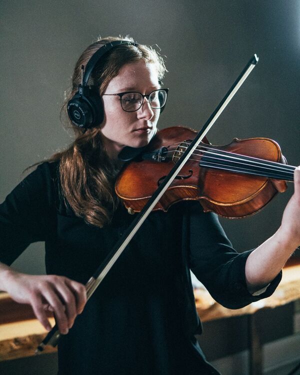 Michelle playing violin in a well light room.