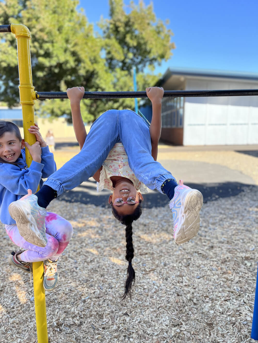 a student laughing as she's flipping upside down on the monkey bars