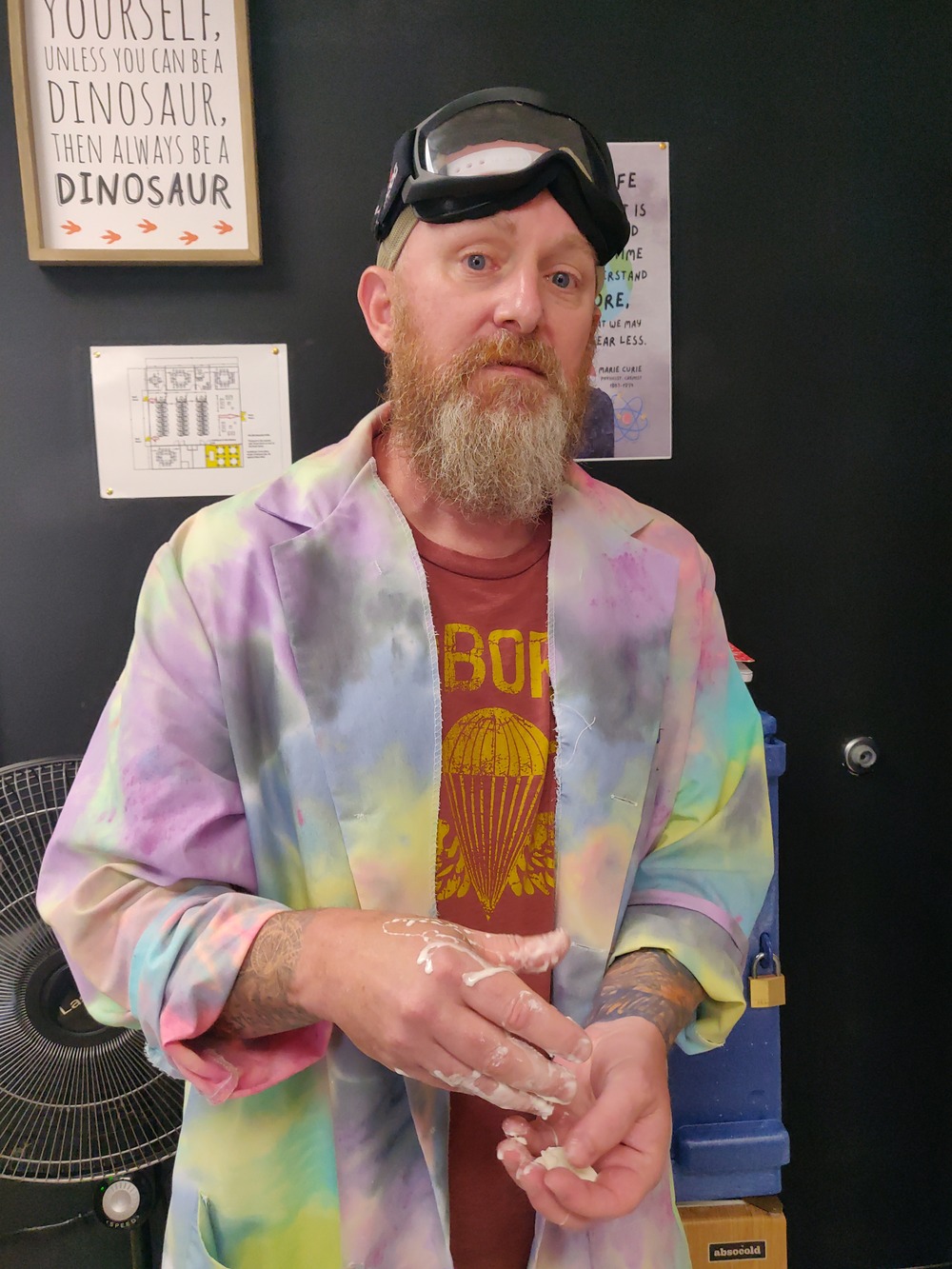 Brad standing with goo in his hands, googles on his head, wearing a tie-dye lab coat.
