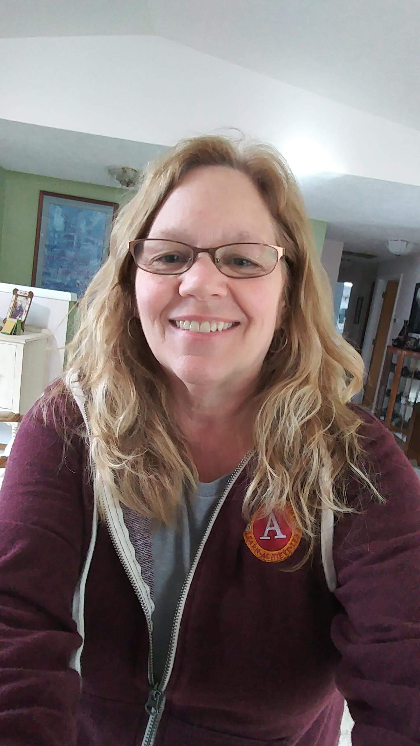 Janette wearing an Abiqua sweatshirt, smiling in her home.